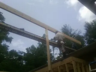 Carpenter setting a ridge beam over a new addition frame — Ice Dam Removal by Roofing Brothers in Winchendon