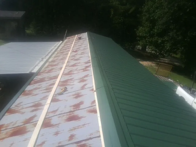 Old rusted panels beside newly installed green metal roofing — Wind Damage Roof Repair by Roofing Brothers in Winchendon