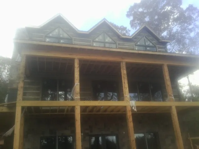 Dormers and porch framing on a large log home under construction — Roof Coating work by our crew in Winchendon