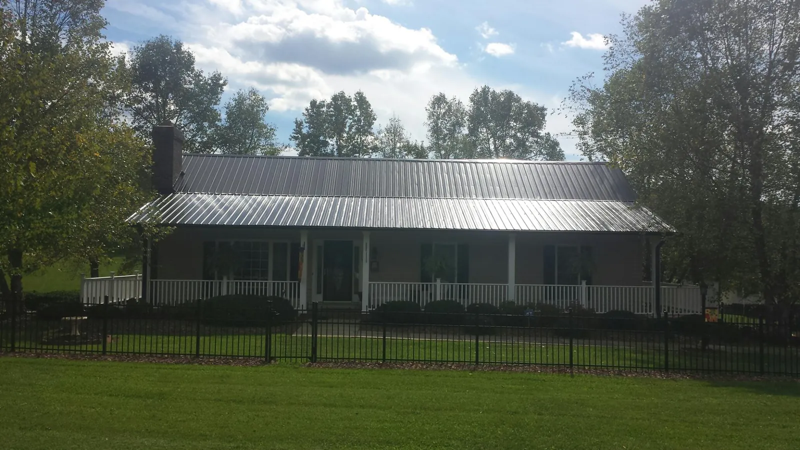 Gray metal roof on a brick ranch with a full width front porch — Gutter Guard Installation work by our crew in Winchendon