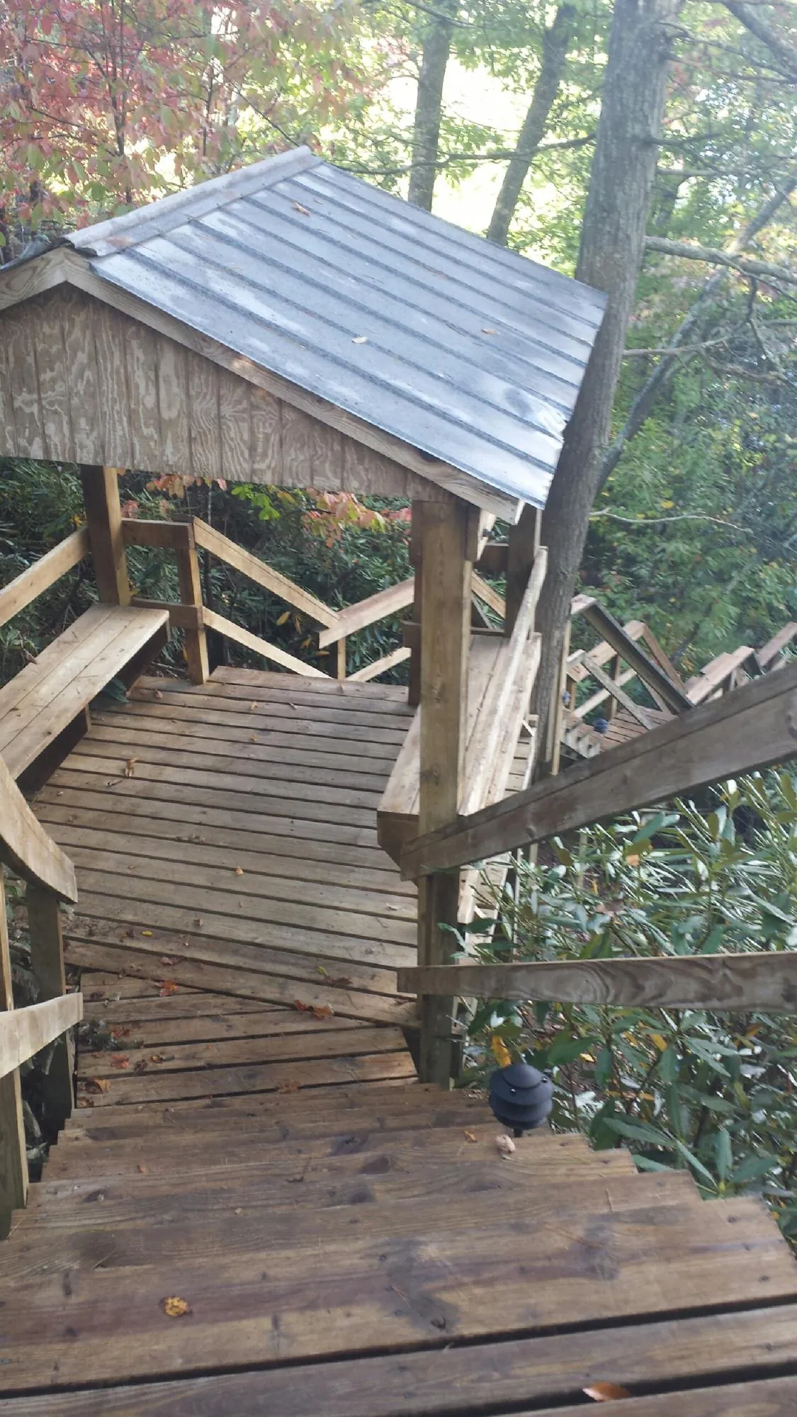 Metal roofed shelter over wooden steps on a wooded walkway — Skylight Repair & Installation work by our crew in Winchendon
