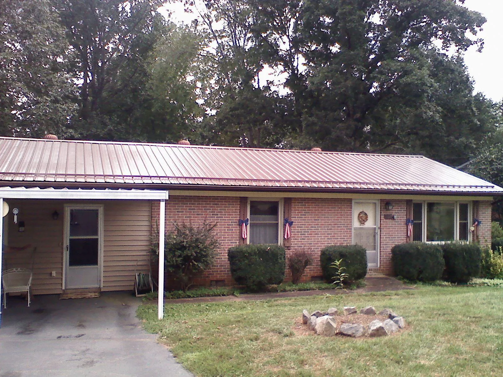 Bronze metal roof and carport on a brick ranch home — Roof Repair work by our crew in Winchendon