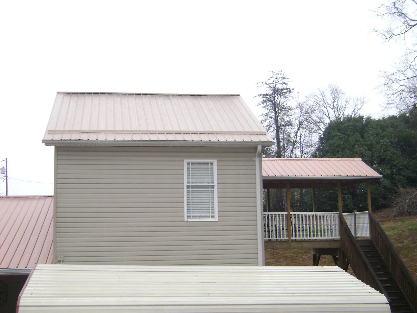 Tan metal roofs on a two story addition and attached porch, from a Roof Replacement job in Winchendon