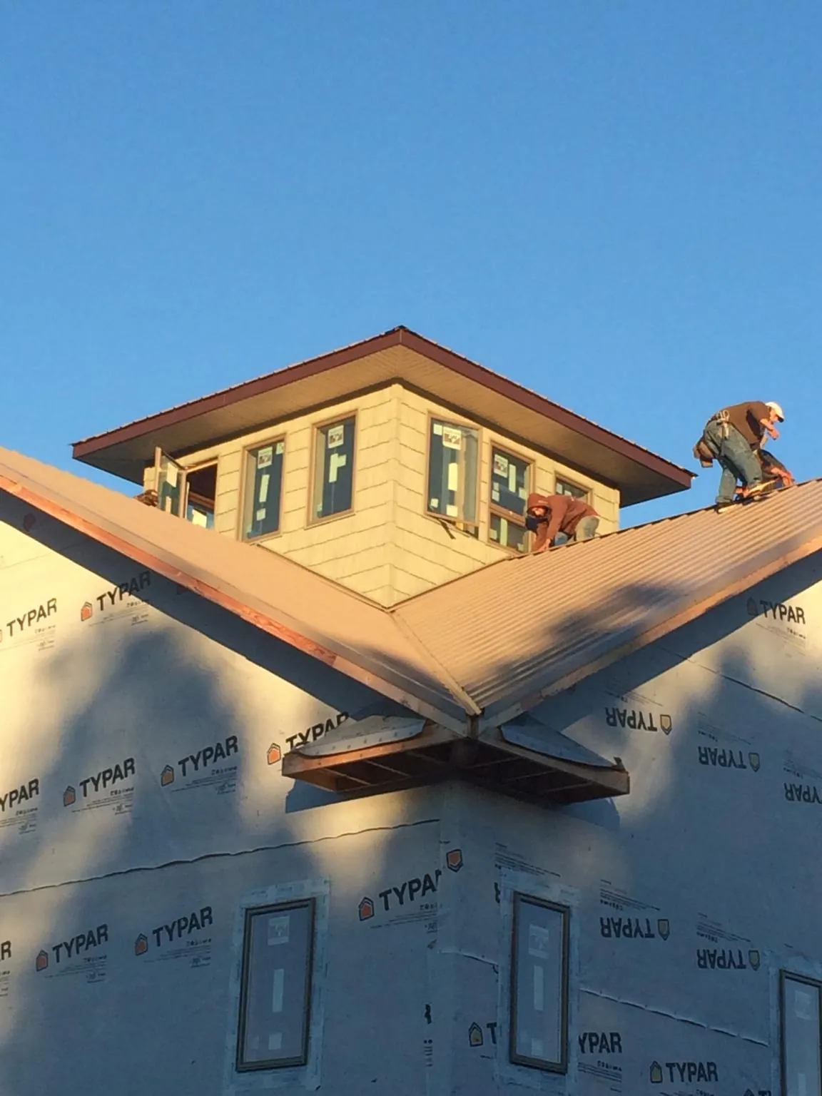 Roofers working around a rooftop cupola on a new metal roof at sunset — Roof Waterproofing in Winchendon by Roofing Brothers